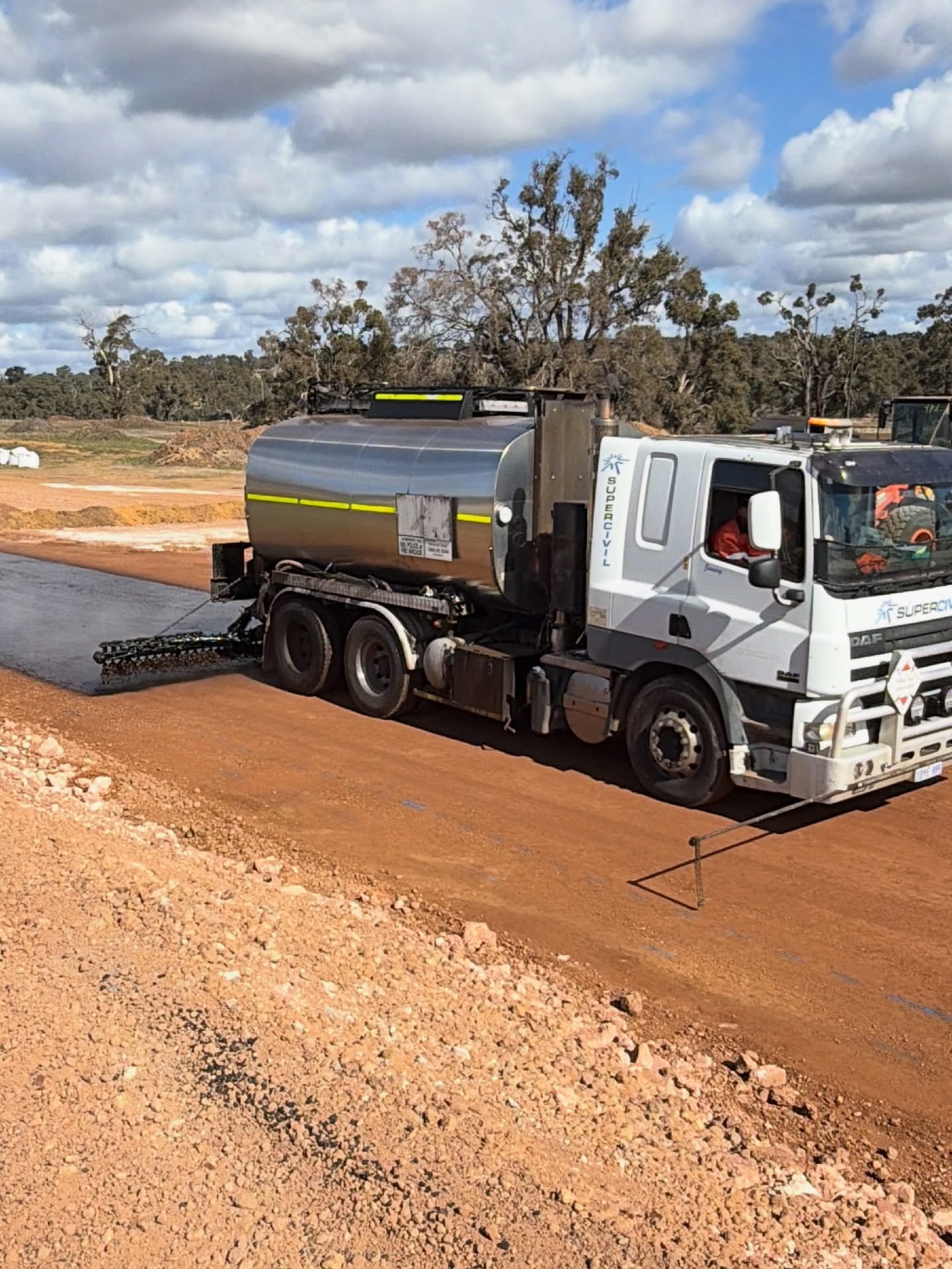 YongaCivil-branded bitumen sprayer truck applying spray seal to a rural red-dirt road in regional Western Australia
