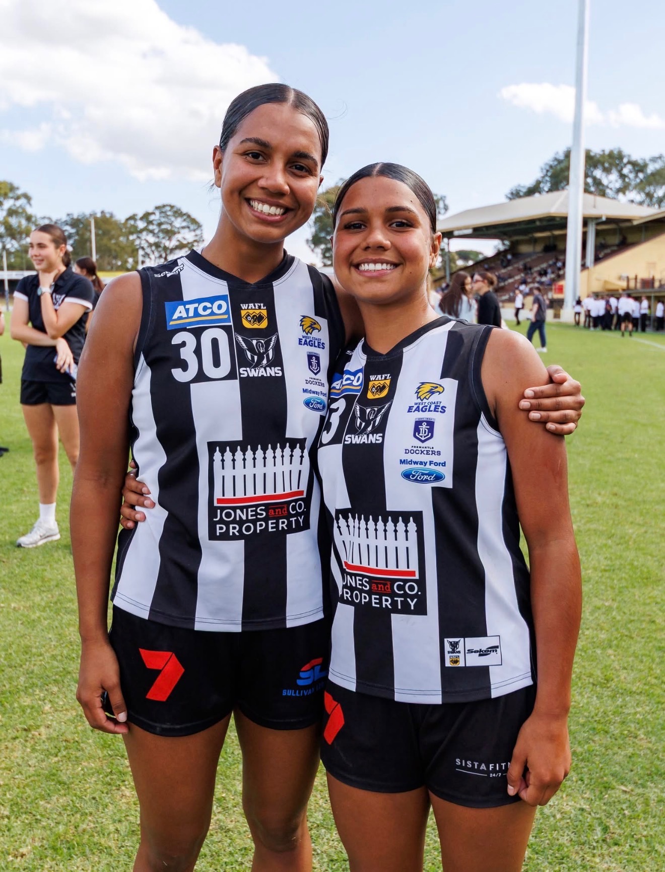 Summer Yarran wearing number 30 and Shaya Yarran wearing number 13 smiling together in Swan Districts jerseys on the football oval